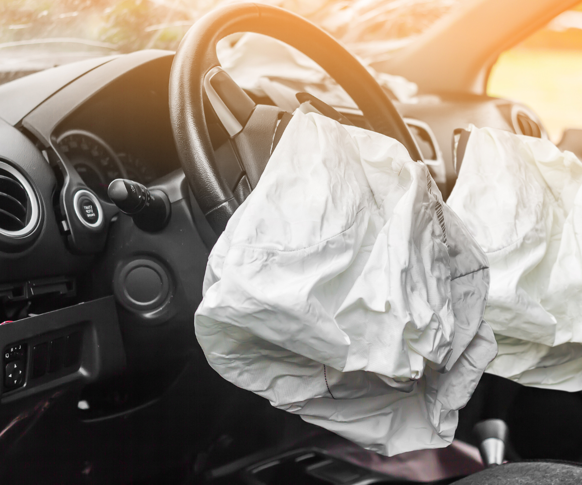 The deployed driver and passenger airbags visible inside a damaged vehicle after a serious car accident.