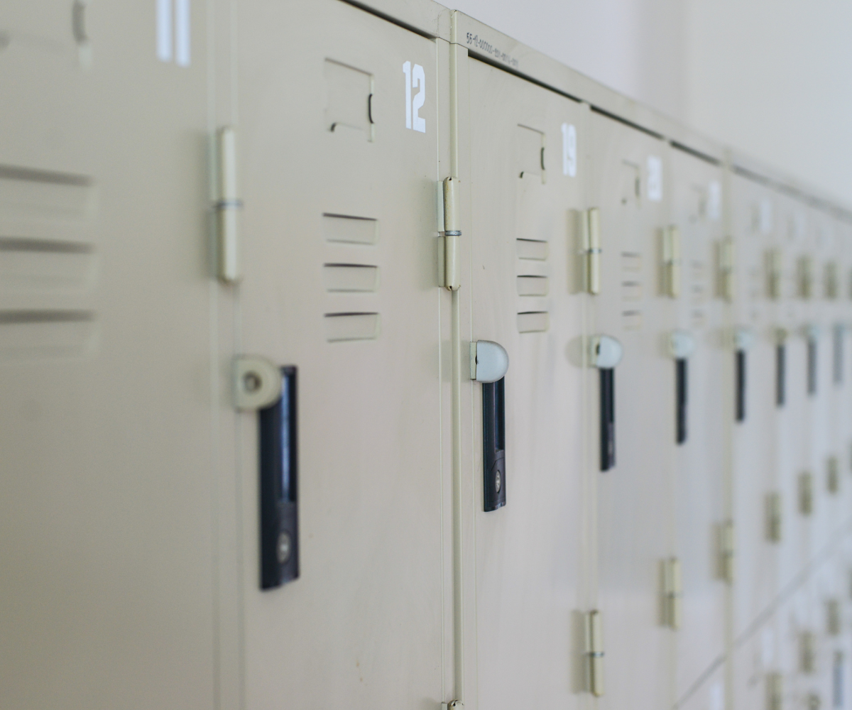 A perspective shot showing a long line of numbered, light-beige metal lockers with black handles receding into soft focus.