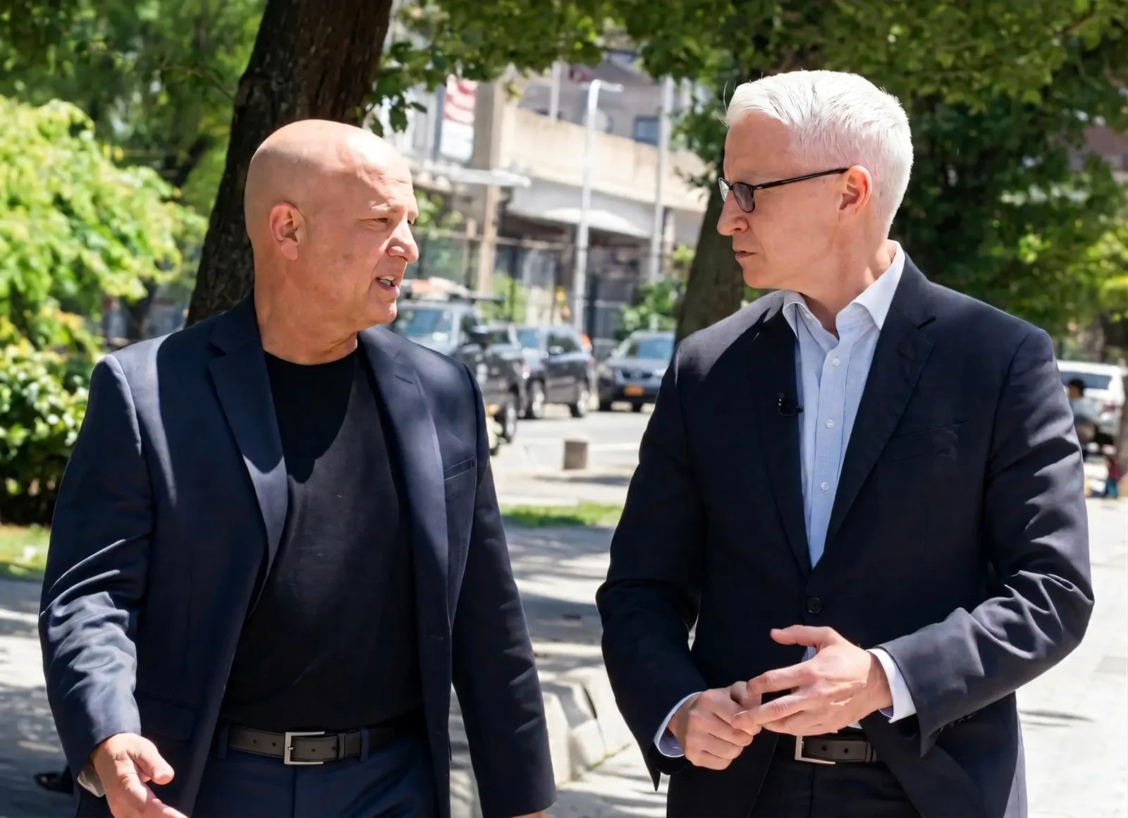 Attorney Doug Fierberg speaks to Anderson Cooper, who is wearing glasses and listening intently. Both men are outdoors in dark suits.